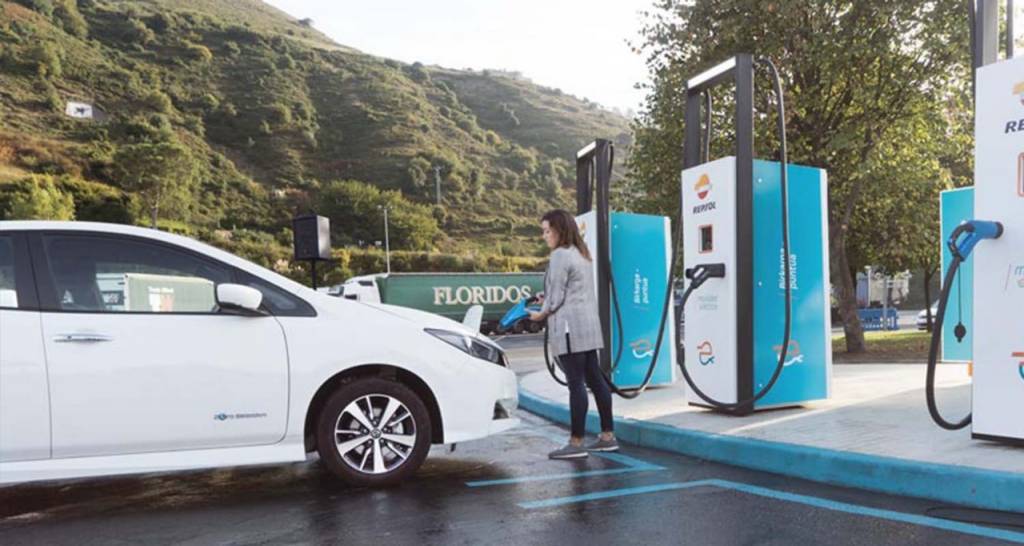 Una mujer en un punto de recarga de un coche eléctrico