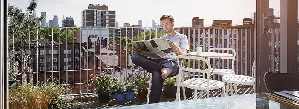 A man reading a newspaper in a balcony