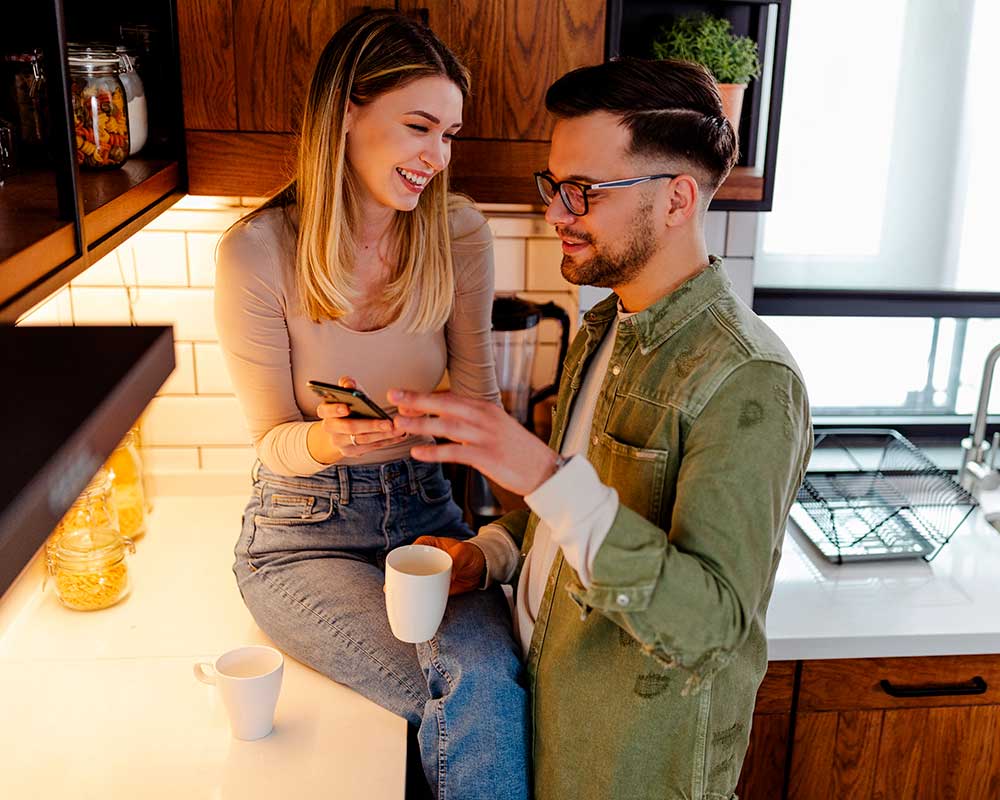 Pareja feliz en la cocina con smartphone