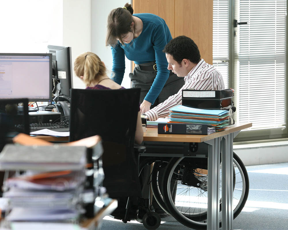 Different abilities. An employee in a wheelchair moving down a hallway