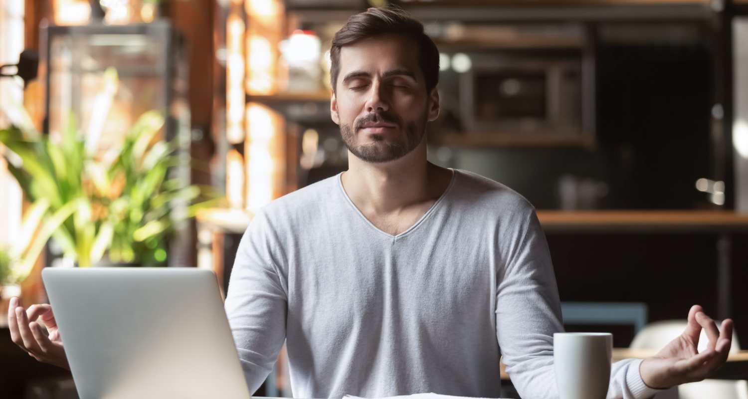 A man meditating in front of a computer