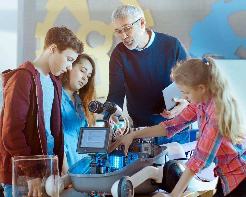 Un grupo de niños manipula un robot junto a un tutor. Telus Spark