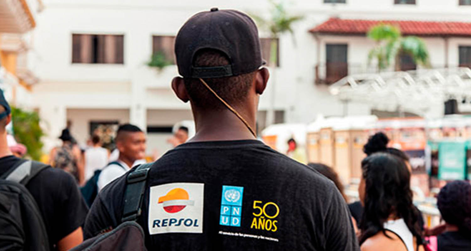 A person with his back turned wearing a black T-shirt with the Repsol logo.