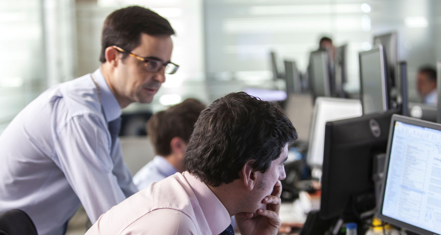 Varios empleados concerando alrededor de una mesa de trabajo