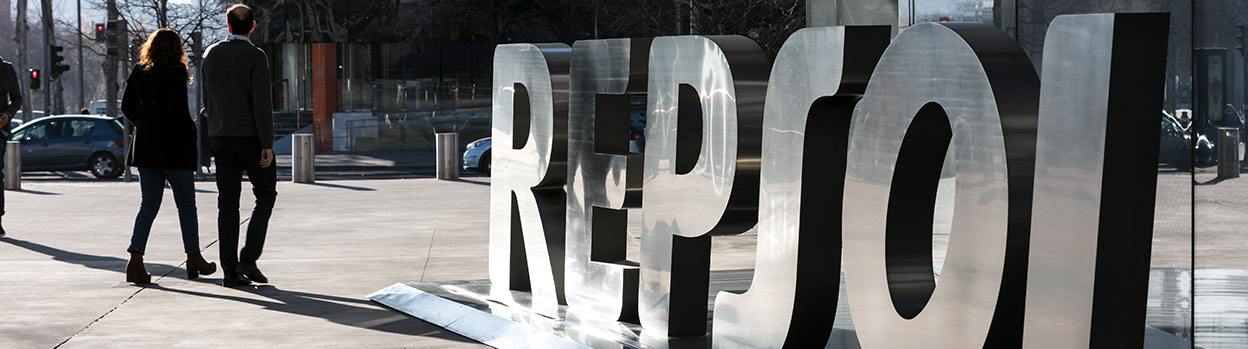 Campus entrance with Repsol logo and people walking around.